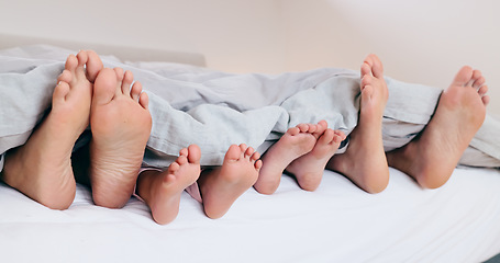 Image showing Family, feet and sleeping in bed, morning or relax together with kids and parents under blanket. Foot, closeup or children rest with mom and dad in bedroom with comfort in home on vacation or holiday