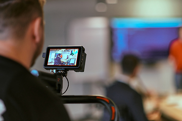 Image showing A cameraman films a director leading a meeting in a modern startup office