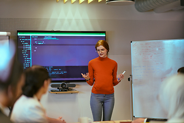 Image showing A pregnant business woman with orange hair confidently presents her business plan to colleagues in a modern glass office, embodying entrepreneurship and innovation