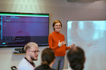 Image showing A pregnant business woman with orange hair confidently presents her business plan to colleagues in a modern glass office, embodying entrepreneurship and innovation