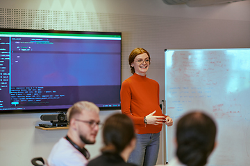 Image showing A pregnant business woman with orange hair confidently presents her business plan to colleagues in a modern glass office, embodying entrepreneurship and innovation