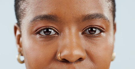 Image showing Eyes, looking and portrait of black woman in studio for vision, eyesight and focus on blue background. Healthcare, optometry and isolated face closeup of person with cosmetics, wellness and eye care