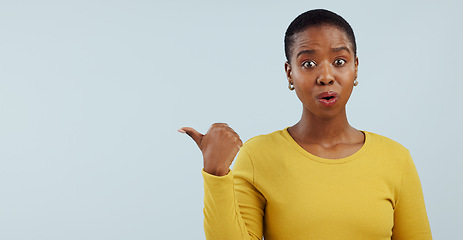 Image showing Surprise, news and portrait of black woman with hand pointing in studio for wow announcement on grey background. Emoji, face and African model show unexpected results, giveaway or secret promotion