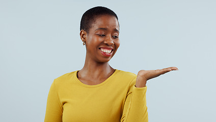Image showing Happy black woman, smile and palm for advertising or marketing against a studio background. Face of African female person with hand out showing advertisement, platform or presentation on mockup space