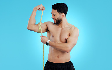 Image showing Happy man, measuring tape and bicep in fitness, bodybuilding or weight loss against a blue background. Male person, athlete or bodybuilder smile taking muscle or arm measurement for flex on mockup