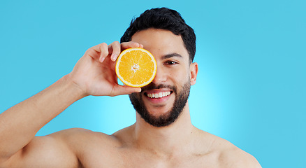 Image showing Orange, skincare or portrait of man in studio for vitamin C, natural cosmetics or healthy diet on blue background. Fruit, beauty and model face with citrus skin detox, cleaning or wellness nutrition