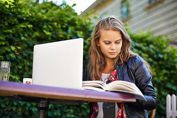 Image showing Woman, book and laptop by cafe outdoors and sitting for reading, assignment or work. Young, female student and technology for online, submission or document for research, project or college test