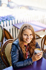 Image showing Portrait, happy and woman at outdoor cafe, drink and restaurant table. Face, smile and person at coffee shop with tea cup, espresso and customer with latte to relax in city cafeteria in Switzerland