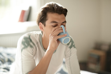 Image showing Relax, morning and a man drinking coffee in the bedroom of his home to relax or wake up on the weekend. Tea, caffeine or beverage with a young person on his bed in an apartment to enjoy a beverage