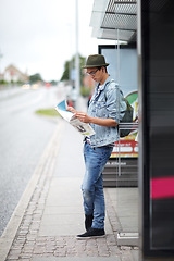 Image showing Man, journey and bus stop with map, travel and adventure by commute, transportation and planning for trip. Male person, information and guide for direction, navigation and vacation or earphones