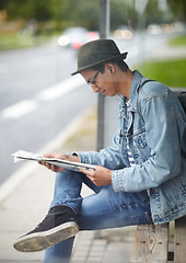 Image showing Man, commute and bus stop with newspaper, travel and adventure on journey, transportation and reading for trip. Male person, earphones and headlines or music, smile and happy for article in outdoors