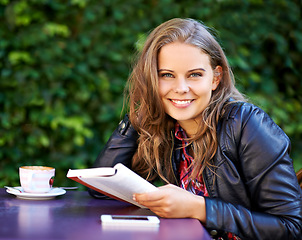 Image showing College student, portrait and reading a book at coffee shop on university, campus or restaurant. Happy, woman and learning from studying books, textbook or relax with knowledge at outdoor cafe