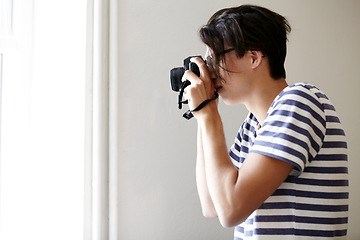 Image showing Man, camera and photographer by window, creative and art in apartment, pictures and inspiration. Male person, confident and photography or lens, vintage technology and retro equipment or gadget