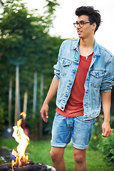 Image showing Man, fire and smile in backyard outdoor for barbecue, celebration or party on grass of house or home. Person, happiness and flame in garden or lawn for bbq, woods or camping in forest or nature