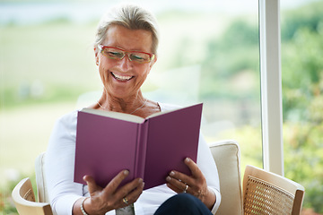 Image showing Senior woman, home and book with reading, chair or relax in living room with smile for story, knowledge or glasses. Happy elderly lady, person and thinking in lounge in retirement with novel in house