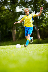 Image showing Sports, man and a soccer player kicking a ball on a field for training, a game or match on a green pitch. Health, fitness or exercise and a young athlete playing football for freedom with energy