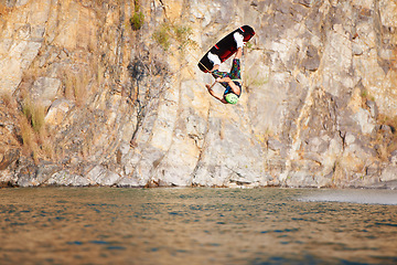 Image showing Man, wakeboarding and lake for jump in air, sport and fitness for speed in summer sunshine. Person, athlete and ski with rope for safety on ocean, sea or river for training, exercise or free on waves