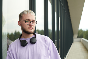 Image showing In front of a modern glass building, a young, blond influencer strikes a confident pose, epitomizing urban glamour and style in the heart of the city