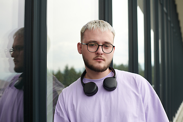 Image showing In front of a modern glass building, a young, blond influencer strikes a confident pose, epitomizing urban glamour and style in the heart of the city