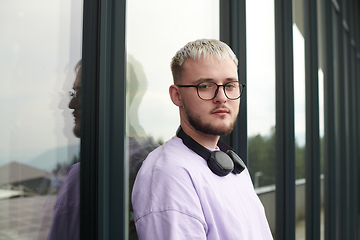 Image showing In front of a modern glass building, a young, blond influencer strikes a confident pose, epitomizing urban glamour and style in the heart of the city