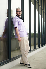 Image showing In front of a modern glass building, a young, blond influencer strikes a confident pose, epitomizing urban glamour and style in the heart of the city