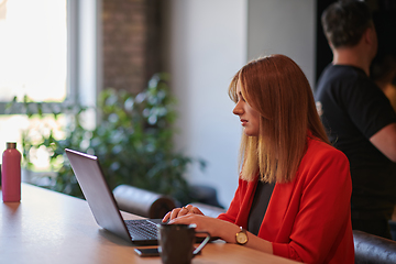 Image showing In a contemporary office setting, a young businesswoman is focused on her laptop, displaying dedication and efficiency in her work