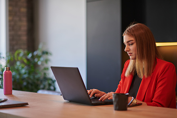 Image showing In a contemporary office setting, a young businesswoman is focused on her laptop, displaying dedication and efficiency in her work