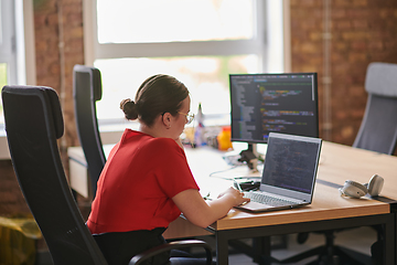 Image showing In a contemporary office setting, a young businesswoman is focused on her laptop, displaying dedication and efficiency in her work