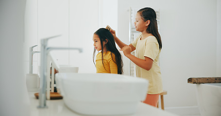 Image showing Family, bathroom and a girl brushing the hair of her sister in their home for morning routine or care. Kids, beauty or haircare with a young child and helping sibling in their apartment for love
