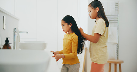 Image showing Family, bathroom and a girl brushing the hair of her sister in their home for morning routine or care. Kids, beauty or haircare with a young female child and sibling in their apartment for hygiene