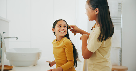 Image showing Family, bathroom and a girl brushing the hair of her sibling in their home for morning routine or care. Kids, smile or haircare with a happy young child and sister in their apartment for hygiene