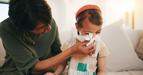 Image showing Grandmother, sick kid and sneeze in home living room for allergy, covid or virus on sofa. Grandma, girl child and tissue for cold, flu and bacteria, disease and care or mature woman help blowing nose