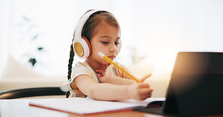 Image showing Girl, headphones and writing in book for elearning, education or study on desk at home. Female person, little child or kid taking notes with tablet, headset or technology for virtual class at house