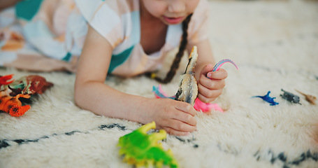Image showing Girl child, dinosaur toys and floor with playing, development and relax with game in room at family house. Kid, plastic reptile and carpet with hands, flooring or animal for fantasy, learning or home