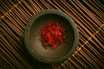 Image showing Saffron threads in a small bowl. Spices, cooking ingredients, flavor.