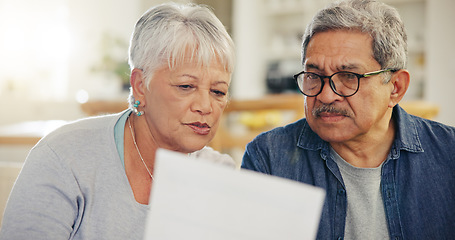 Image showing Senior couple, bills and reading paperwork in home for budget, planning investment and financial assets. Man, woman and discussion with documents for banking, retirement savings and insurance policy