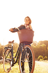 Image showing Countryside, nature and portrait of happy woman with bicycle, adventure or travel in morning. Summer, smile and bike with a basket at sunset and person in sunshine with transportation for cycling