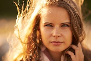 Image showing Serious, woman and portrait in nature at sunset in autumn, spring or environment in summer. Calm, face and girl relax with hair in the wind with golden, sunshine and light at sunrise in morning