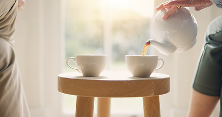 Image showing Pot, pour and hands with tea cup in morning, home and closeup on drink, steam and table. Hot, beverage and person with hospitality, service and drinking in the afternoon with friends in living room