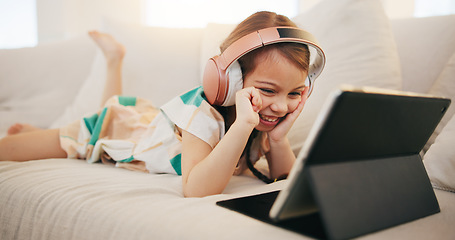 Image showing Happy little girl, tablet and headphones on sofa for elearning, entertainment or streaming at home. Female person, child or kid smile on technology in relax for movie, education or learning at house