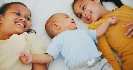 Image showing Love, family and sisters with baby boy on a bed for bonding, relax and conversation at home together. Happy, care and girl children lying with little brother in a bedroom with comfort and security