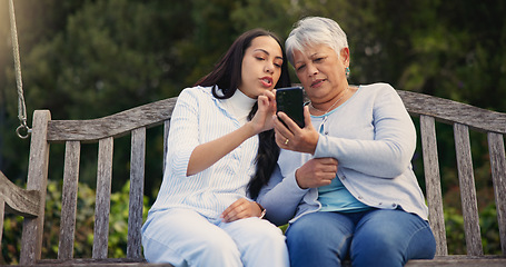 Image showing Phone, senior or mother with woman on bench in nature reading news on social media in retirement. Online gossip, mature parent or daughter for together in park or garden as a family with mobile app