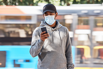 Image showing Man in city with mask, phone and morning travel at bus stop, checking service schedule or social media. Public transport safety in covid, urban commute and person in street with smartphone connection