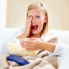 Image showing Horror, popcorn and woman on sofa watching tv with remote, blanket and streaming movies in home. Terror, television and girl on couch in living room with fear for scary video, film or network show.