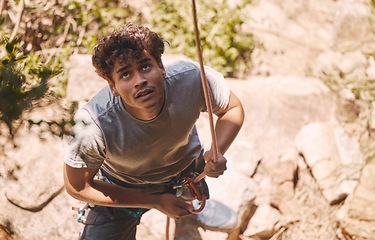 Image showing Man on rock in nature, climbing mountain with with safety equipment and outdoor clothes to show courage. Young healthy guy hiking cliff, on extreme fitness adventure or exercise journey.