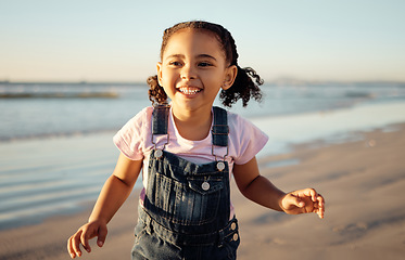 Image showing Energy, freedom and black girl running at beach, happy and excited about view of the ocean at sunset. Sea, travel and summer fun by child enjoying fresh air on a seaside getaway playing and laughing