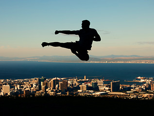 Image showing Silhouette of man doing karate with sky and city in the background. Outline of male athlete punching and kicking in the air in martial arts motion. Motivation, inspiration and urban warrior