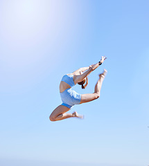Image showing Fitness, jumping and sky with a sports woman mid air outdoor against a clear blue background during summer. Workout, exercise and training with a female athlete leaping for health and wellness