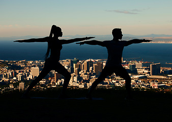 Image showing Yoga, silhouette and city with a couple outdoor for exercise, workout and training. Health, wellness and fitness with a man and woman exercising outside together on an urban background in the evening