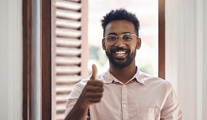 Image showing Thumbs up, endorsing and thank you with a young man smiling, feeling positive and giving his approval while standing inside. Portrait of a happy male wearing glasses and giving his trust or support